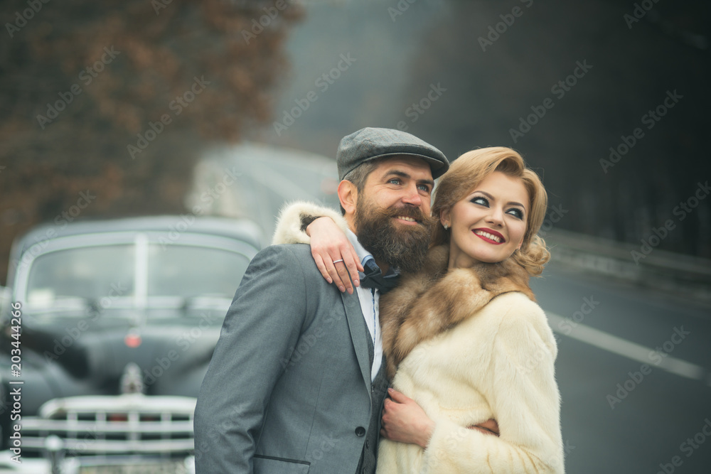 brutal bearded man with a mustache with a girl near retro car