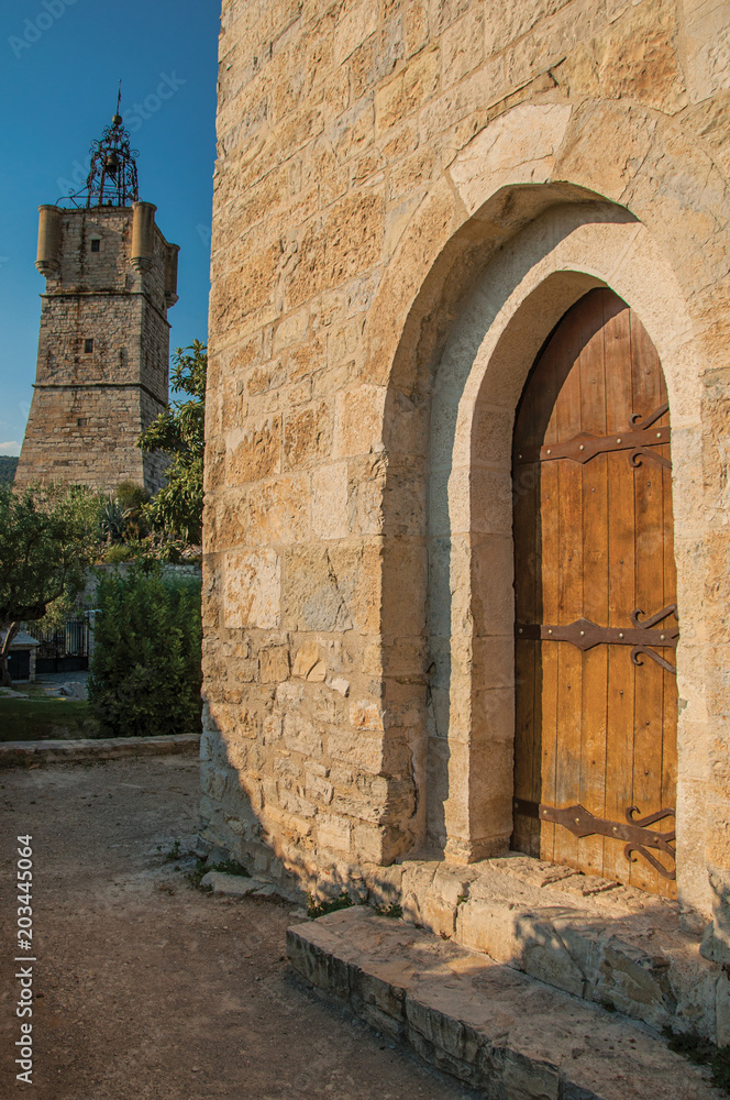 View of the clock tower made of stone on top of the hill and wooden ancient door in the lively and gracious town of Draguignan. Located in the Var department, Provence region, southeastern France