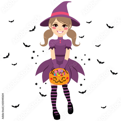 Beautiful young teenager witch wearing purple dress holding trick or treat pumpkin bag