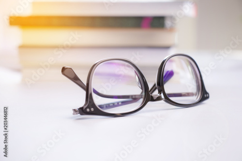 Stylish black glasses on a white background and blurred books.