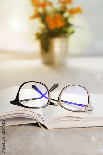 Stylish black glasses on a book. Blurred background.