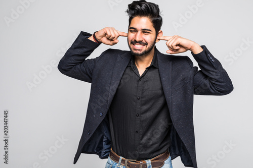 Handsome young indian man covered his ears by he is finger and screaming, he can not stand the noise, isolated on white background.