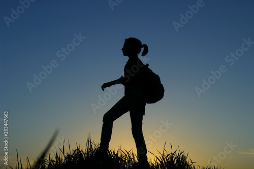 People, Teens, Hiking and Travel Concept. Silhouette Of A Young Girl On A Mountain Top.Young Girl With Backpack Enjoying Sunset.Tourist Traveler At Sunset. 