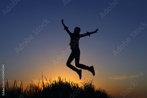 Happy Girl Enjoying A Life At Sunset.Silhouette Of A Young Girl Relaxing At Sunset Sky Outdoor. People, Freedom, Travel Concept.Girl Jumping At Sunset Background. 