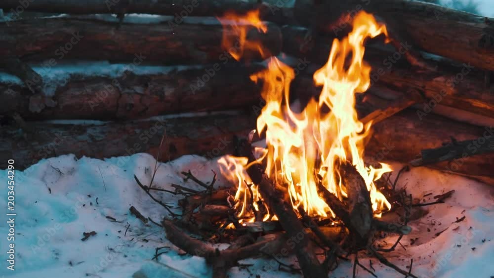Campfire in the winter forest in slow-motion, travel survival concept, winter fun expedition, hiking and active lifestyle