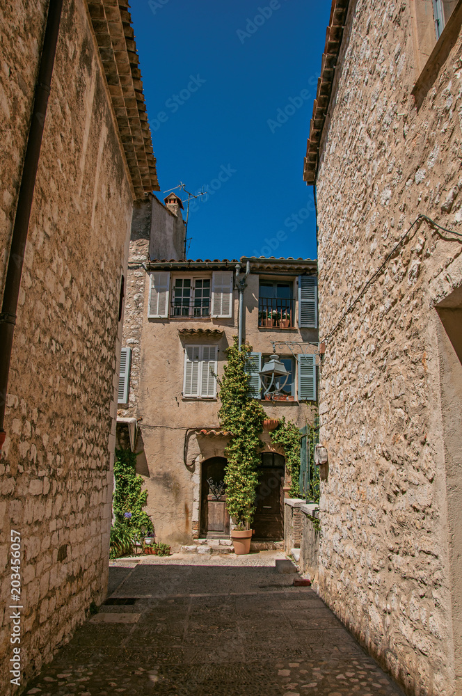 Alley view with stone walls, house and plants in Saint-Paul-de-Vence, a lovely well preserved medieval hamlet near Nice. Located in Alpes-Maritimes department, Provence region, southeastern France