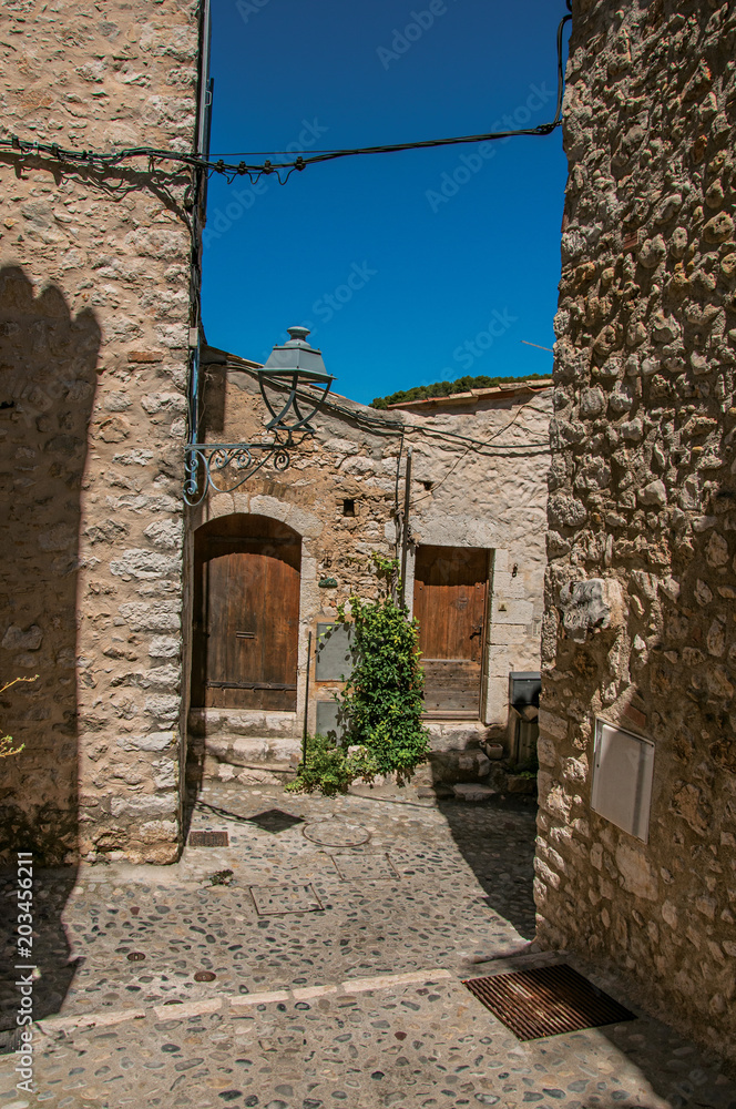 Naklejka premium Alley view with stone walls, house and plants in Saint-Paul-de-Vence, a lovely well preserved medieval hamlet near Nice. Located in Alpes-Maritimes department, Provence region, southeastern France