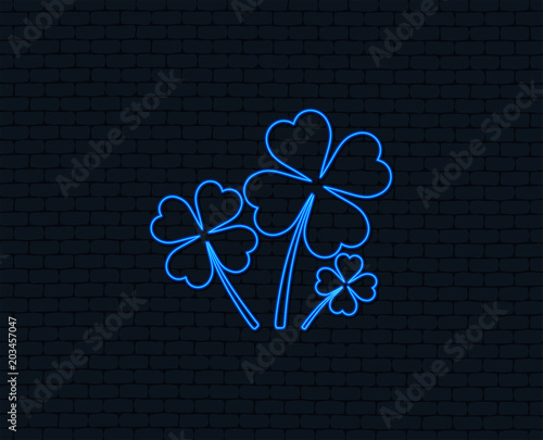 Neon light. Clovers with four leaves sign icon. Saint Patrick symbol. Glowing graphic design. Brick wall. Vector photo