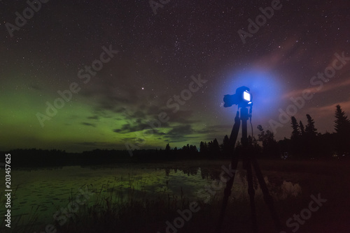 Aurora reflecting of a lake, city lights lighting up clouds - Camera in forground © Ryan