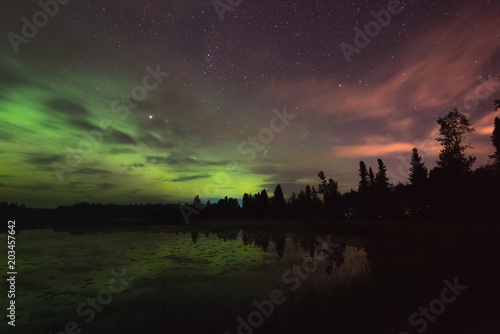Aurora reflecting of a lake, city lights lighting up clouds 