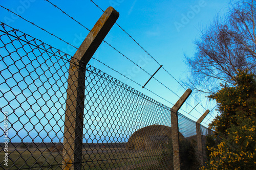 Barbed chainlink fence with a blue sky at the abandoned Air Force base of Rendlesham, UK