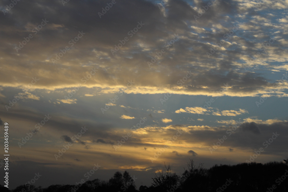 Obraz premium Blue sky with an assortment of clouds and an amazing sunset with treest and foliage in the foreground