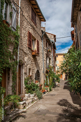 Alley view with stone houses and plants in the morning sun in Vence, a stunning medieval hamlet completely preserved. Located in the Alpes-Maritimes department, Provence region, southeastern France