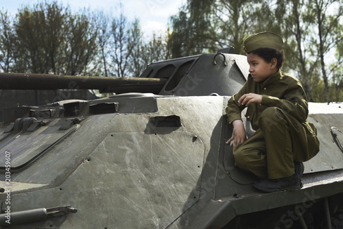 Boy on the war. Child schoolboy on a tank. The boy in the form of a soldier during the Second world war of 1941-1945. photo