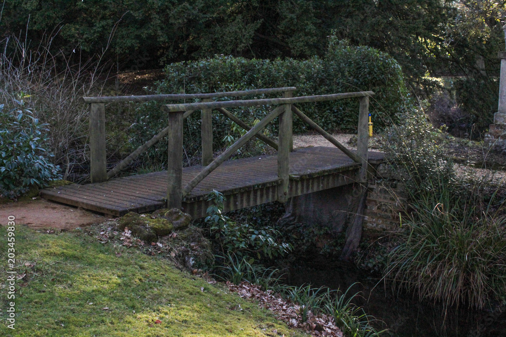 Fototapeta premium Wooden footpath bridge crossing a stream