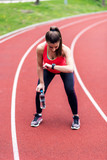 Female runner looking at smartwatch after running on racetrack