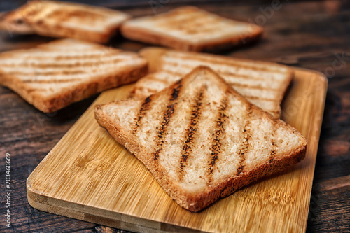 Tasty toasted bread on wooden board, closeup