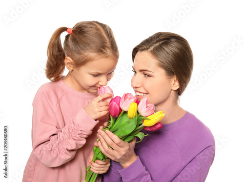 Portrait of mother and cute little daughter with flowers on white background