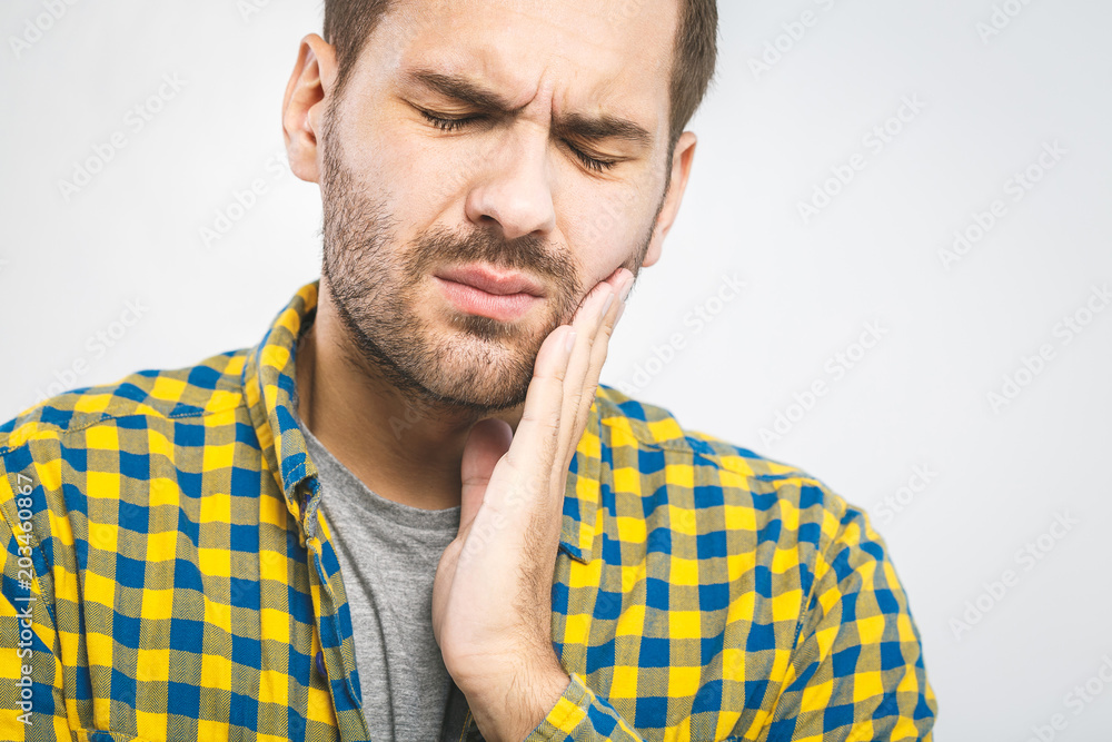 toothache. Handsome young man suffering from toothache, closeup, touching his cheek to stop pain against white background. Strong toothache toothache. Handsome young man suffering from toothache, closeup, touching his cheek to stop pain against white background. Strong toothache