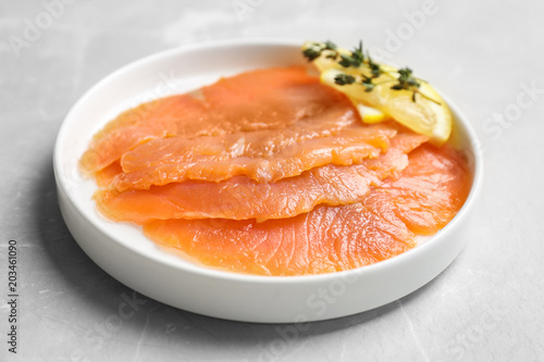 Plate with fresh sliced salmon fillet and lemon on table