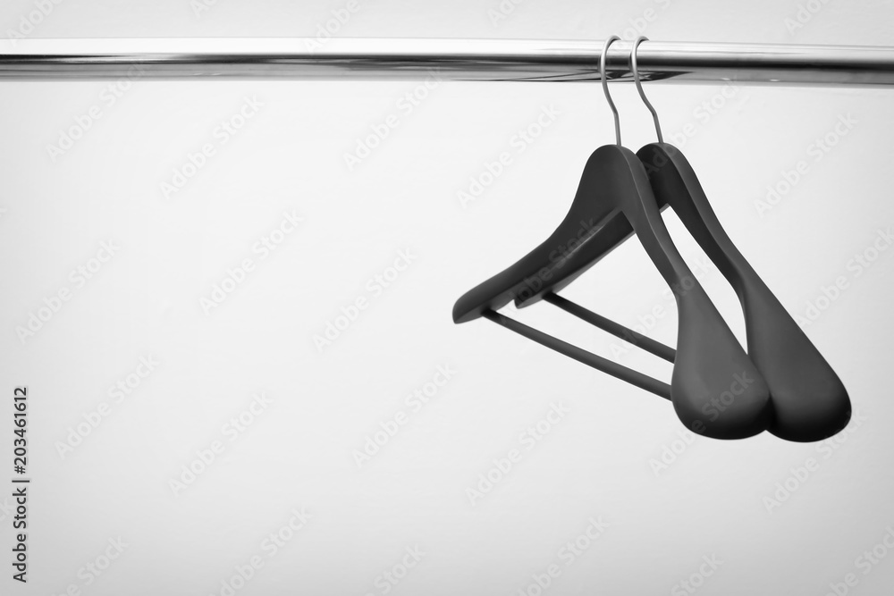 Obraz premium Clothes hangers on metal rail against light background