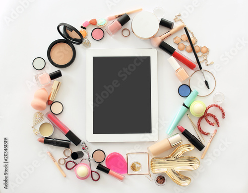 Flat lay composition with makeup products for woman and tablet on light background