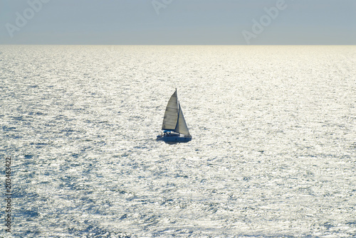 Single yacht floats in dazzlingly bright lit sea