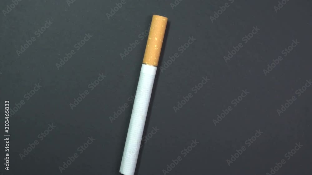 Cigarette close-up, macro shot, slowly spinning on a rotating black background. Cigarette close-up, macro shot, slowly spinning on a rotating black background.