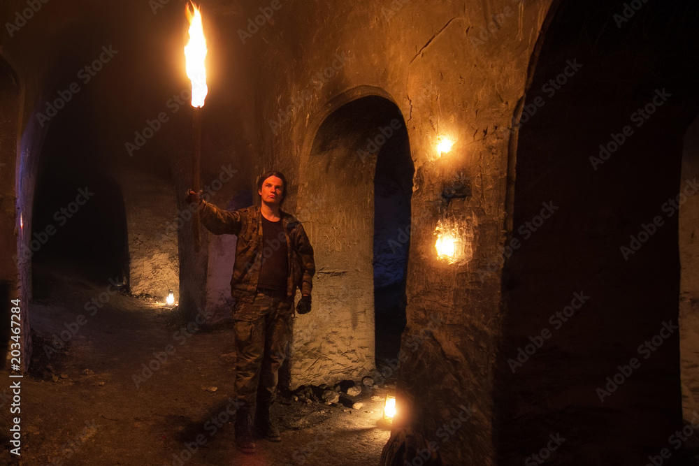 Obraz premium Man with torch explores ancient abandoned underground temple. 