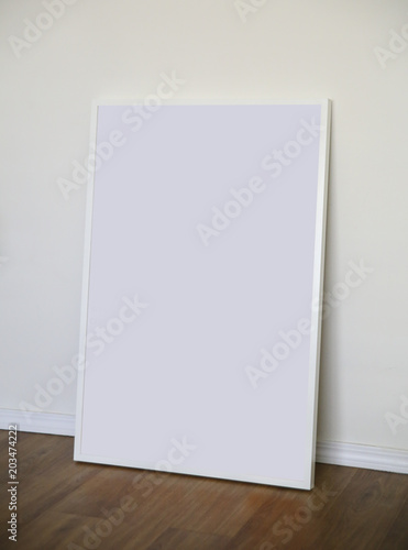 Blank poster in a white frame on the wood floor