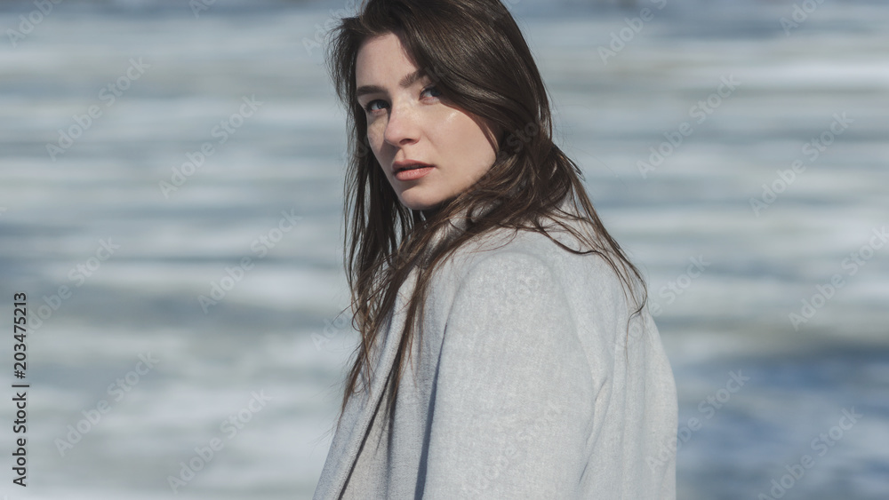 attractive young woman in coat near frozen river attractive young woman in coat near frozen river
