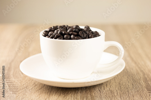 Roasted coffee beans in white glass on the wooden table