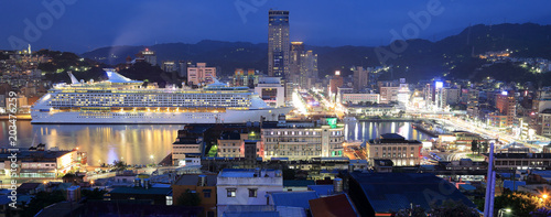 Panorama of Keelung City at dusk  a busy seaport in northern Taiwan  with view of a cruise liner parking in the harbor and buildings by the quayside in blue twilight