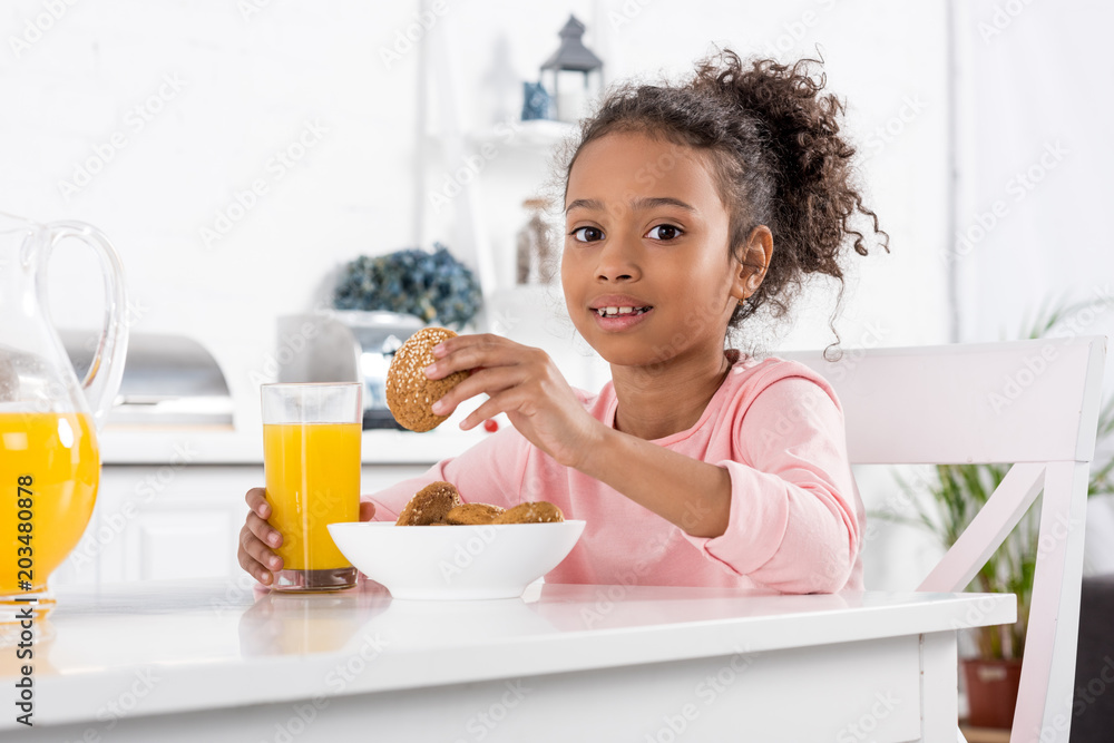 preteen african american kid with orange juice and oatmeal cookies in kitchen preteen african american kid with orange juice and oatmeal cookies in kitchen