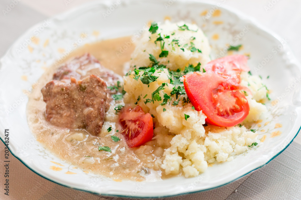 Polish traditional beef cutlets with sauce and potato and tomato slices. Beef cutlets knows in Poland as bitki wolowe. Polish traditional beef cutlets with sauce and potato and tomato slices. Beef cutlets knows in Poland as bitki wolowe.