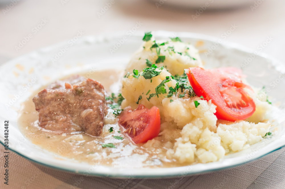 Polish traditional beef cutlets with sauce and potato and tomato slices. Beef cutlets knows in Poland as bitki wolowe. Polish traditional beef cutlets with sauce and potato and tomato slices. Beef cutlets knows in Poland as bitki wolowe.