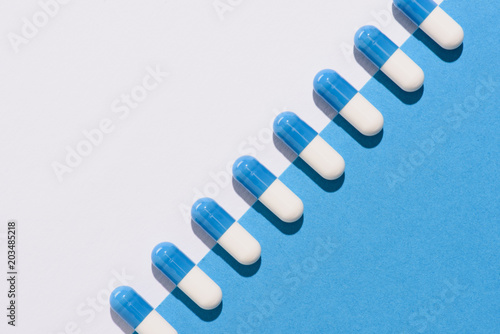 top view of row of pills on halved white and blue surface photo