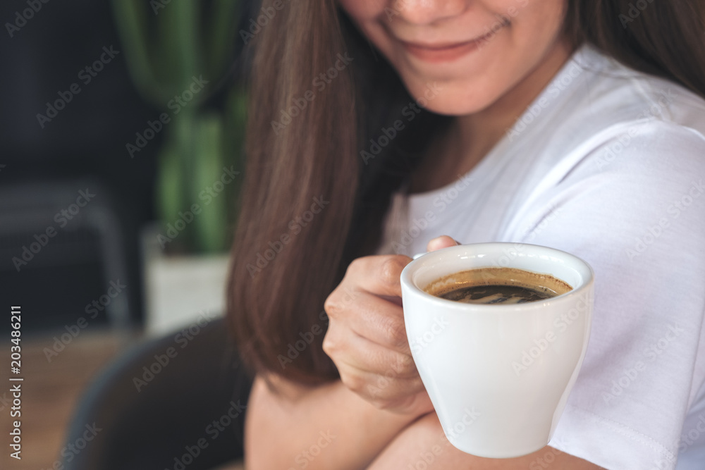 Closeup image of an Asian woman holding a coffee cup before drinking with feeling good in cafe Closeup image of an Asian woman holding a coffee cup before drinking with feeling good in cafe