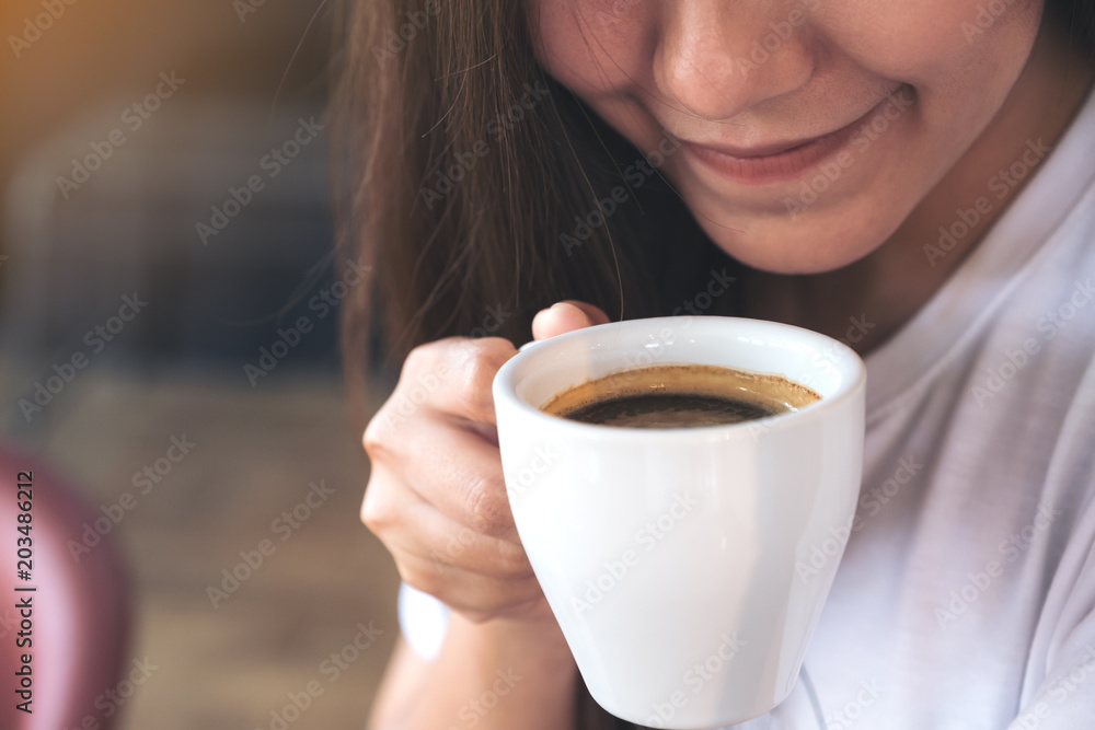 Closeup image of an Asian woman holding a coffee cup before drinking with feeling good in cafe Closeup image of an Asian woman holding a coffee cup before drinking with feeling good in cafe