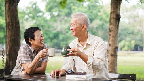 Asian senior couple relax drinking coffee in summer park  green nature