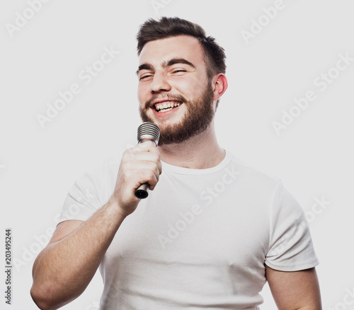 bearded man singing to the microphone. Emotional portrait of an attractive guy with a beard on a white background