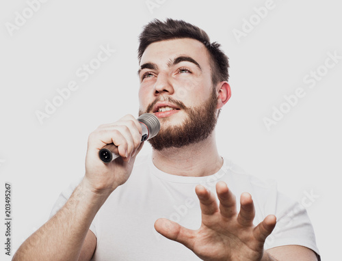 bearded man singing to the microphone. Emotional portrait of an attractive guy with a beard on a white background