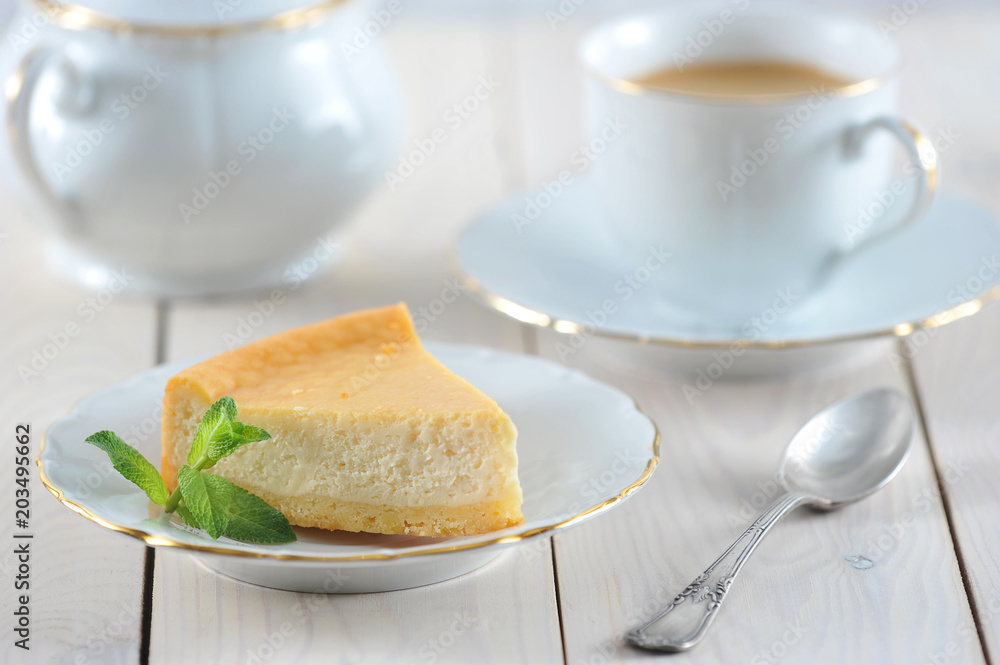 cheesecake and a mint leaf on the saucer with a Golden rim cheesecake and a mint leaf on the saucer with a Golden rim