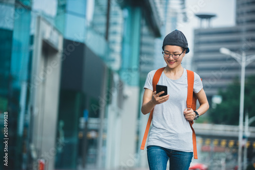 young woman walking with smart phone in modern city photo