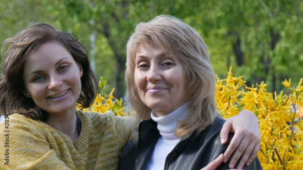 An adult daughter runs up and meets an elderly adult mother hugging her and kissing her. Spring Mother's Day An adult daughter runs up and meets an elderly adult mother hugging her and kissing her. Spring Mother's Day