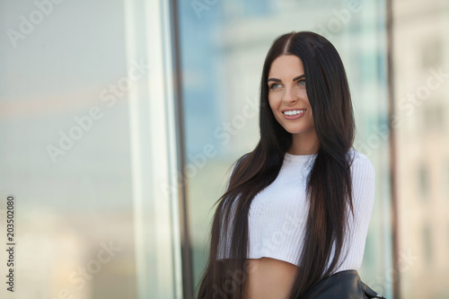 Fashion lifestyle portrait of young happy pretty woman laughing and having fun on the street at nice sunny summer day. portrait of young pretty stylish girl with long hair.