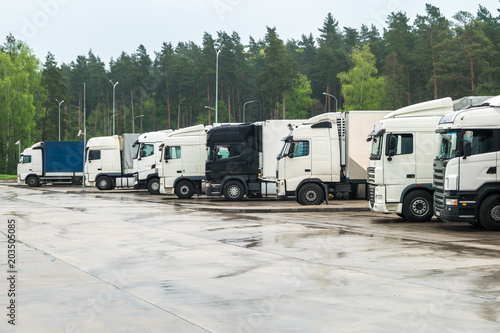 Trucks in a row with containers in the parking lot near forest , Logistic and Transport concept