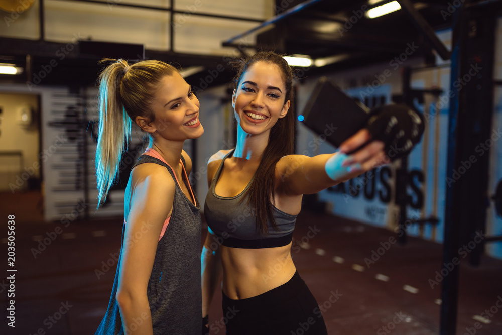 Fototapeta premium Girls are taking selfie during their training in a gym