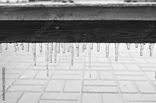 Black and white icicle on a wooden bench after a frozen rain