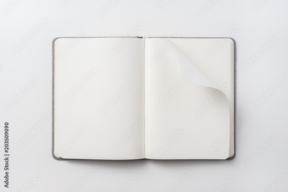 Design concept - Top view of hardcover gray linen notebook with curl blank page isolated on white background for mockup Design concept - Top view of hardcover gray linen notebook with curl blank page isolated on white background for mockup